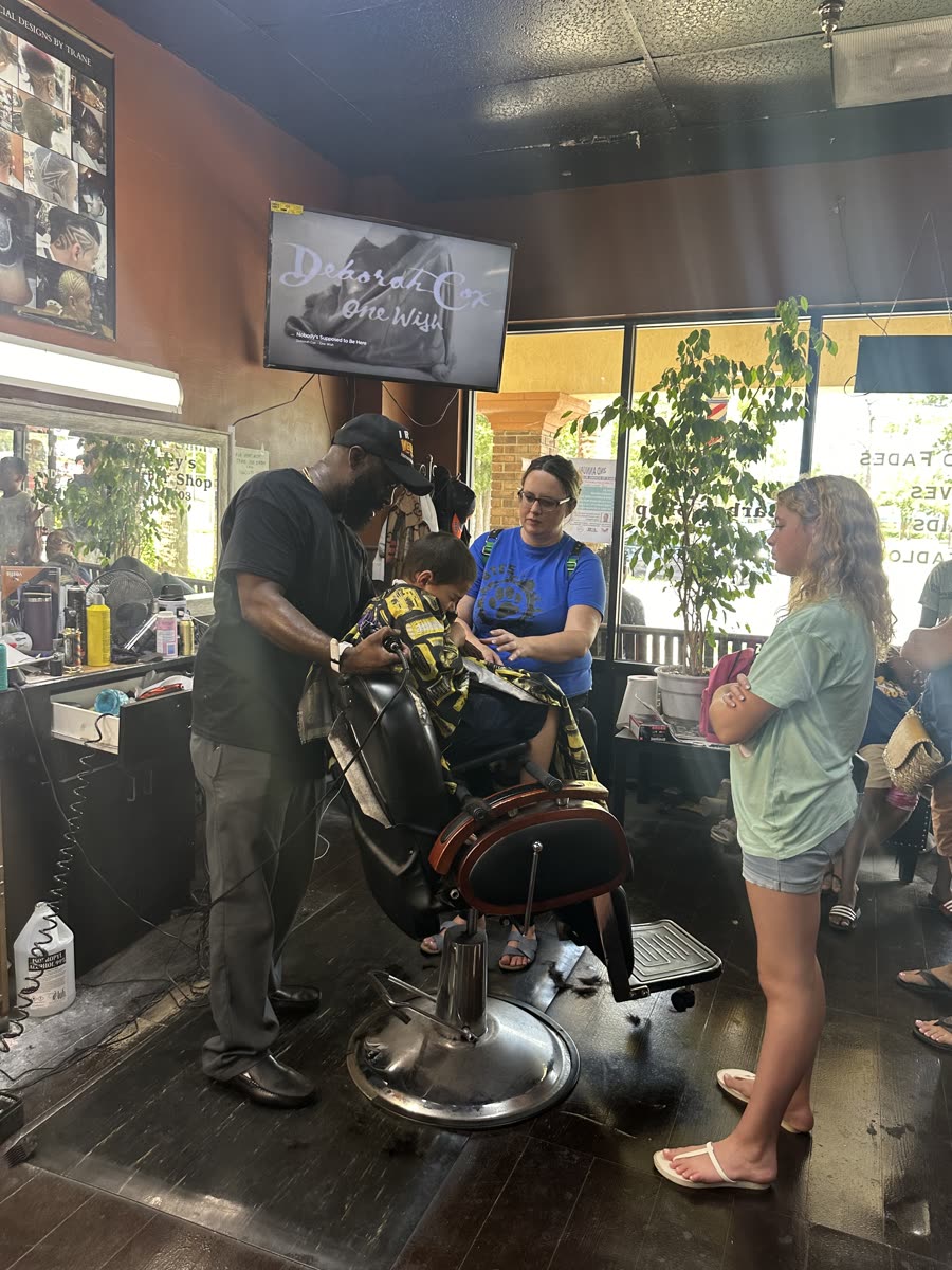 A barber giving a young boy a fresh free haircut at Toney's Barbershop during the Scoops & Subs back-to-school event