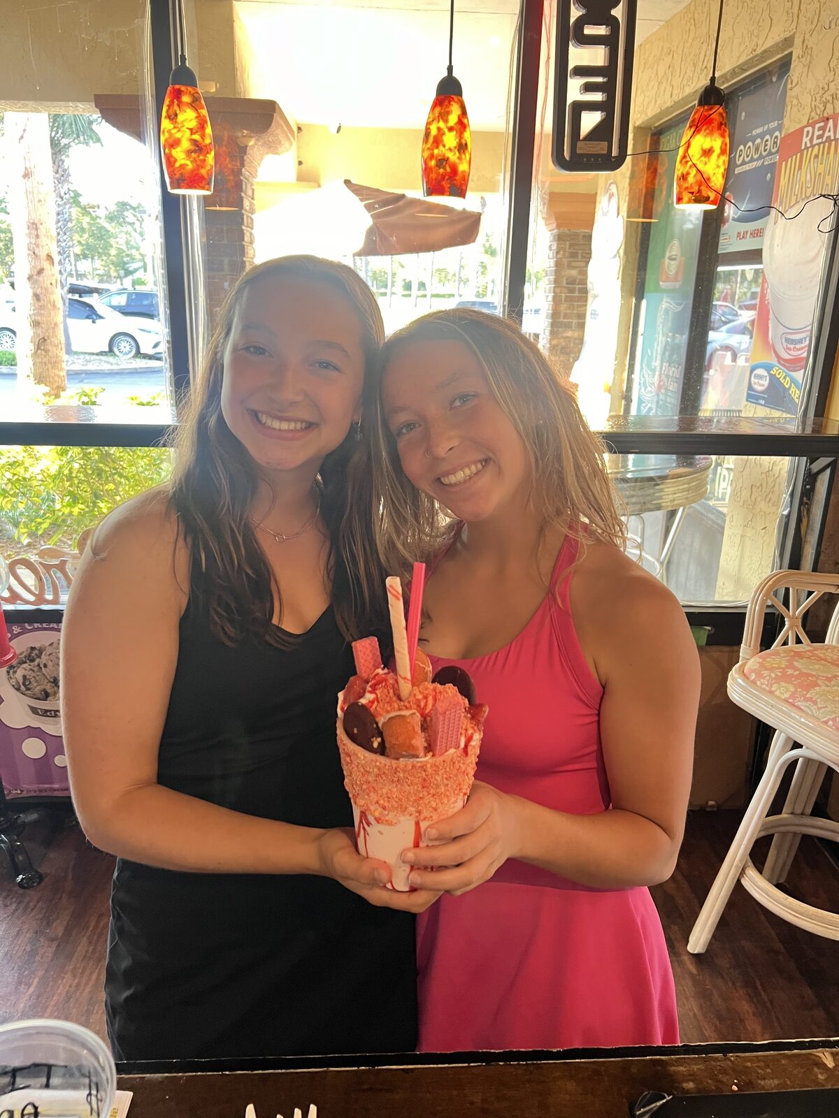 Two friends smiling with a pink Monster Milkshake